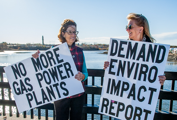 two women holding signs on bridge