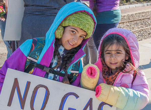 two children in coats holding sign "No Gas"