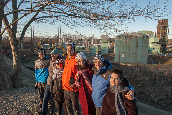 several people stand in a line with power plant in background