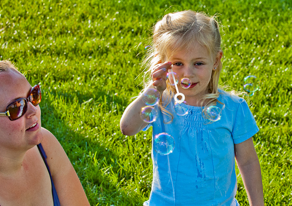 Girl blowing bubbles as woman watches