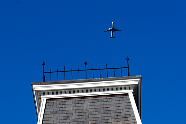 Blue sky with airplane behind old building